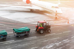 货运牵引车机在机场运送行李车到飞机。机场承运人和服务.