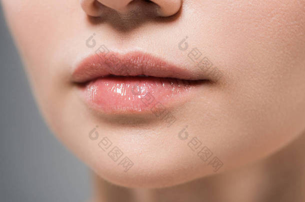 裁剪视图的妇女与柔软的嘴唇隔离在灰色 