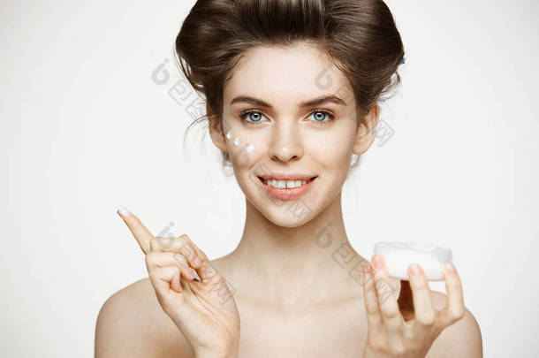 年轻漂亮的黑发女孩在卷发微笑着看着相机膏的脸在白色的背景。面部护理。美容健康和美容.