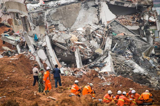 中国救援人员在发生山体滑坡的一座倒塌建筑物的废墟上休息