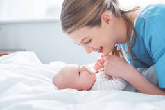在病房里, 快乐的年轻母亲手牵着手可爱的婴儿的侧视图