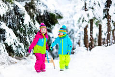 孩子们在雪地上雪橇在冬季公园玩耍
