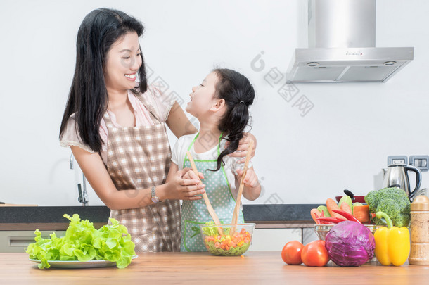 亚洲妈妈和孩子女儿在家里的厨房里做饭