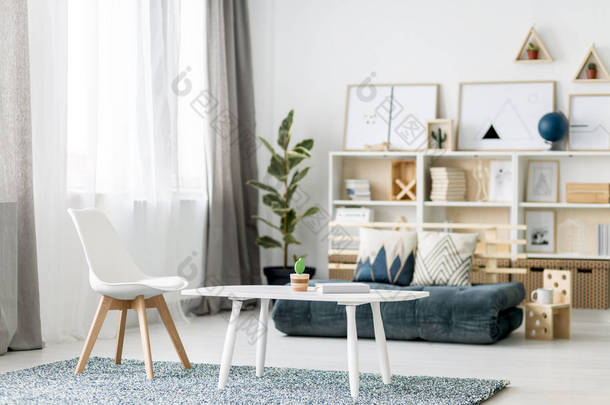 白色咖啡桌与书和小装饰仙人掌和木椅子<strong>站立</strong>在地毯在北欧样式房间内部与窗口