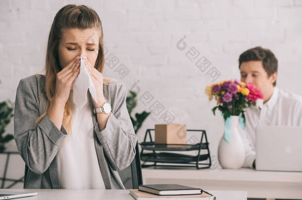 金发碧眼的女商人与花粉过敏打喷嚏在组织附近的同事嗅到鲜花在办公室 