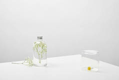 瓶与天然美容产品和白色野花在灰色背景