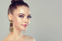 美丽的模特女孩与时尚化妆和化妆品。大金色闪亮耳环首饰 .