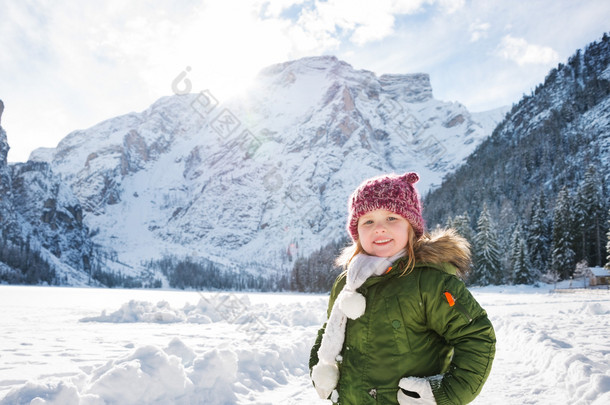 穿着绿色外套的快乐孩子站在雪山前