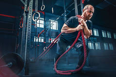 战斗绳子战斗的男人的绳索在健身房锻炼。运动量来找到.