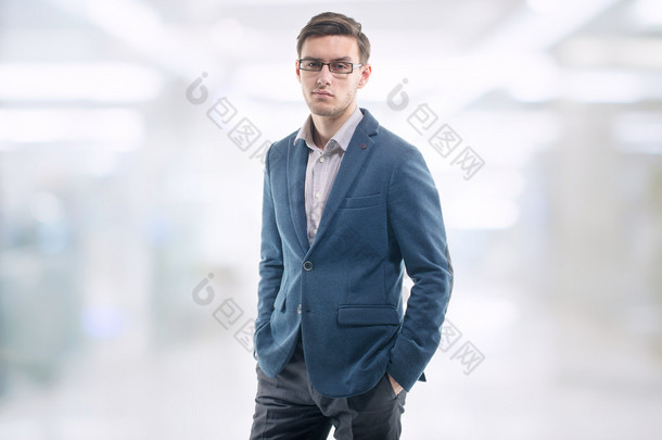 年轻的帅小伙，在办公室里戴着眼镜，独自对著他的手的口袋