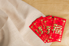 中国新年装饰品红色信封在木头和麻袋 (外国文本意味时运 或 好运)