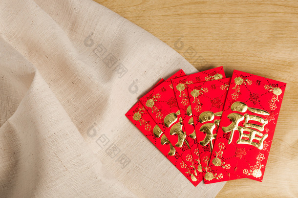 中国<strong>新年</strong>装饰品红色<strong>信封</strong>在木头和麻袋 (外国文本意味时运 或 好运)