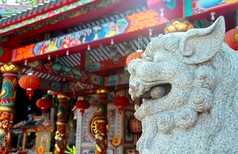 白色的中国监护人狮子与华人庙宇背景