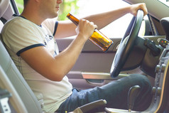 人在驾驶汽车时喝啤酒.