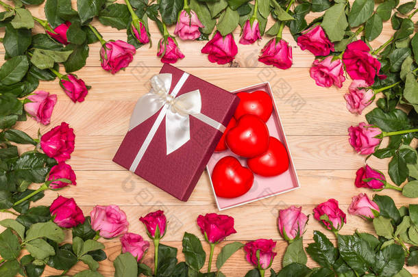 新鲜的粉红色的玫瑰花朵和红色的心木甲板上。为爱或