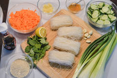 亚洲菜材料︰ 玻璃面条、 黄瓜、 胡萝卜、 酱油、 芝麻、 大蒜、 生姜、 芹菜、 香菜、 葱切木板上.