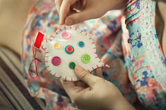 女手缝白色棉心与按钮不同的颜色。手工制作的爱情观. 