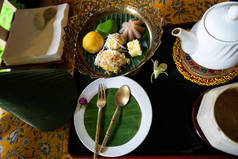 下午茶时间一套泰国传统甜点与香蕉叶和花卉装饰花卉图案桌布