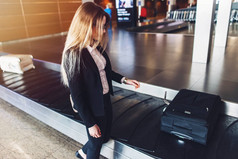 年轻女商人从行李认领处得到她的行李在机场