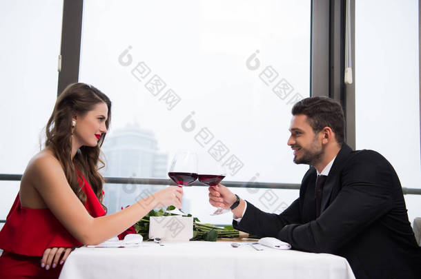 在庆祝情人节在餐厅的情侣无比杯红酒的侧面视图