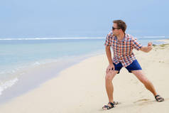 快乐的白种人玩沙滩投掷石头在海洋上, 巴厘岛