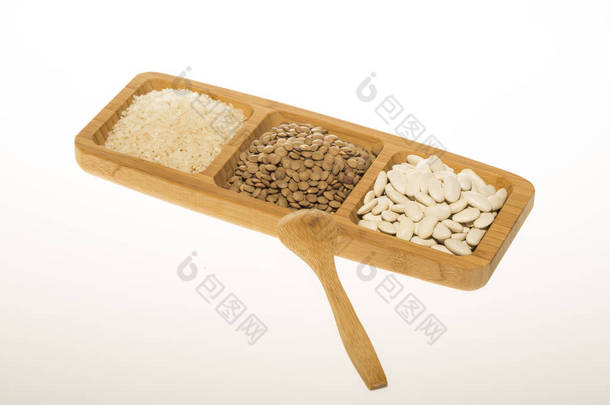 原白芸豆、扁豆和大米在木制的盘子和木勺上隔绝白色的底色, 顶部的景色。宏, 关闭.