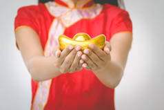 亚洲女子用旗袍捧着金子。春节.