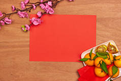 热门饰品中国春节装饰品. 桔子, 树叶, 木篮子, 红包, 梅花在红色背景.