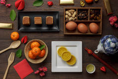 顶部鸟瞰空中拍摄的布置装饰中国新年和农历新年假期的背景概念。平躺在新鲜的橙色与食物和饮料在现代褐色木在家庭办公室书桌.