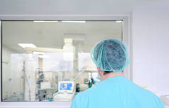一名男子外科医生在医院的手术室里看着玻璃