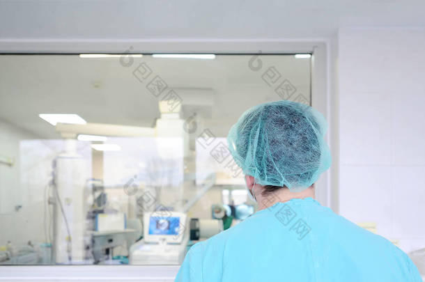 一名男子外科医生在<strong>医院的</strong>手术室里看着玻璃