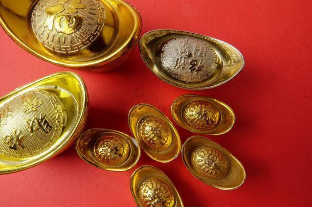 金锭为农历新年喜庆装饰品在红色背景。汉字意味着运气, 财富和繁荣, 如图所示.