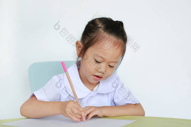 穿着校服的亚洲<strong>儿童</strong>在白色背景下的桌子上<strong>写字</strong>.