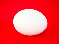 一个真正的大纯白色鸡卵的特写照片在充满活力的红色实心彩色切割板背景下制作一个美丽的眼睛醒目背景复活节假期.