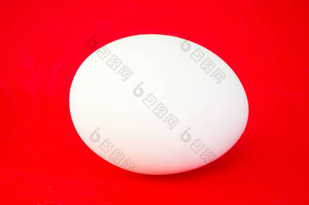 一个真正的大纯白色鸡卵的特写照片在充满活力的红色实心彩色切割板背景下制作一个美丽的眼睛醒目背景复活节假期.