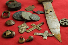 很多古代的铜和铁的对象在红色的背景, 个人物品发现的18世纪在地面上