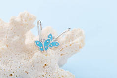 蝴蝶形耳环在蓝色背景与拷贝空间。带复制空间的蓝色背景蝴蝶形耳环