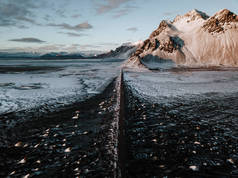 在冰岛 Stokksnes, 一条通向高山的道路, 覆盖着积雪。照片是用无人机拍摄的.