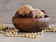 美味的自制核桃卷与美味的黑巧克力在木碗和闪亮的金色珠子链装饰, 关闭传统的圣诞糖果