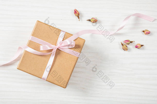 提出了概念。关闭和顶端的米色<strong>工艺礼品</strong>盒在木质背景上的粉红色丝缎带, 复制空间.