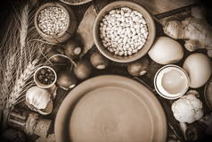 烹调用的食物和香料。放置在粘土板上的文本。在木质背景下的西红柿、蘑菇、花椰菜、黄瓜和鸡蛋.
