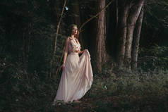 美丽的神秘精灵在优雅的花礼服漫步在树林里