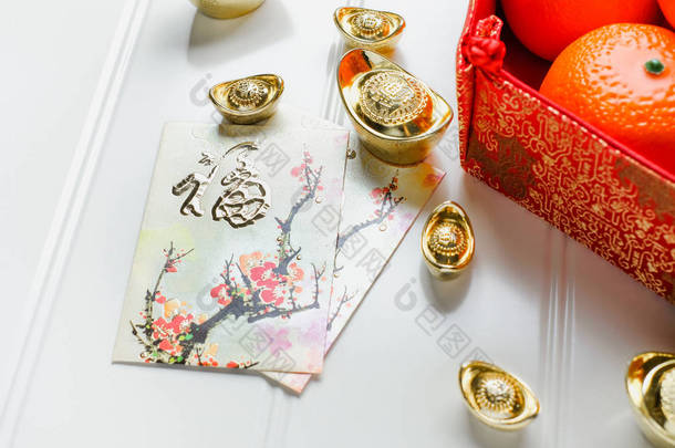 农历新年, 红包包 (昂<strong>战俘</strong>) 和红色毡织物袋与黄金锭和桔子和花在白色的木桌面上, 中国语言意味着幸福和钢锭意味着富裕.