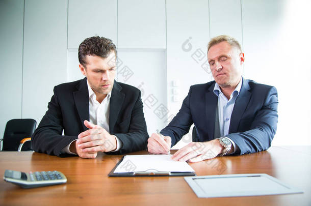 两个商务人员在会议桌上<strong>签</strong>名文档