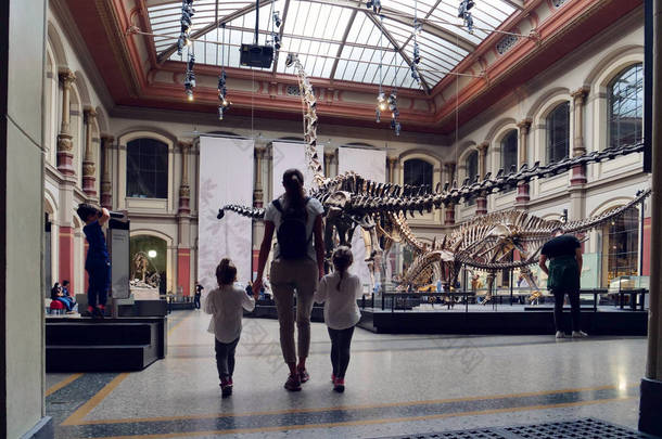 一个家庭去参观考古博物馆, 那里有史前恐龙骨骼。理念: 教育、家庭、学校、历史.
