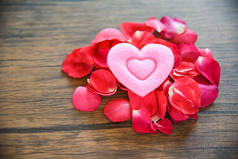 情人节爱心的概念/一堆玫瑰花瓣与粉红色的心装饰在木桌质朴的背景 