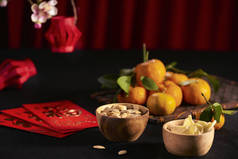 在深色木桌上放入传统农历新年碗中的生姜干糖和南瓜籽