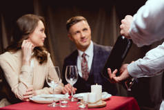 有选择的焦点服务员显示一瓶酒美丽的夫妇在浪漫的约会在餐厅