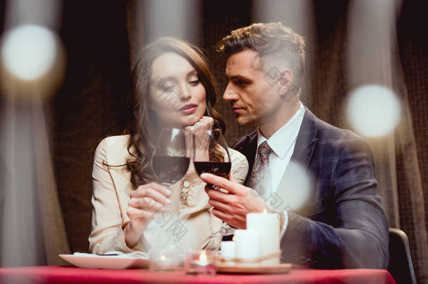 在<strong>餐厅</strong>里, 一对夫妇在浪漫的<strong>约会</strong>中喝着红酒, 前景是波克灯