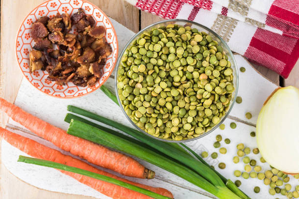 切菜板的顶部视图与干豌豆, 胡萝卜, 洋葱, 熏制煮熟的培根-豌豆熏制培根汤的成分.